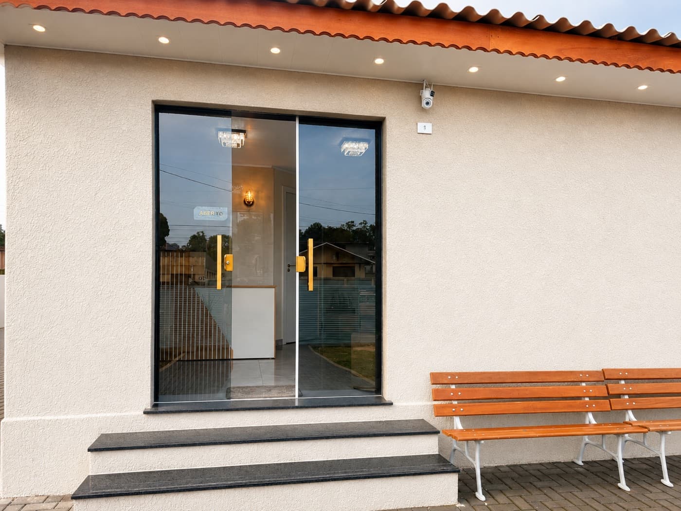 Fachada do consultório, com porta de vidro e bancos na calçada